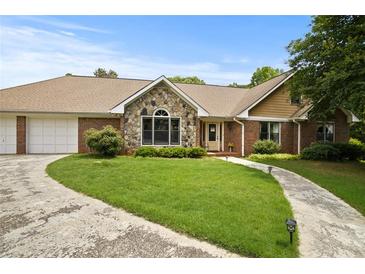 Charming single-story home with stone accents, a well-manicured lawn, and a paved driveway leading to an attached garage at 2139 Bramlett Nw Pl, Marietta, GA 30064