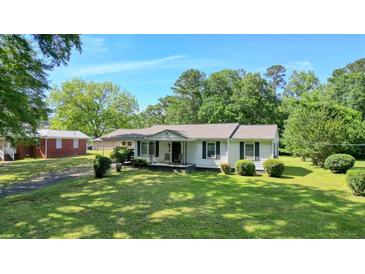 Charming single-story home featuring a well-manicured lawn, dark shutters, and covered front porch at 110 Barnesdale Ter, Woodstock, GA 30188