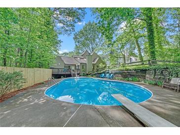 Inviting backyard pool area featuring an in-ground pool, diving board, and surrounding lush greenery at 2505 Oakrill Rd, Marietta, GA 30062