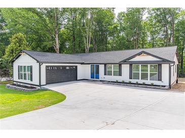 Newly built home with a modern white exterior, dark trim and a well-manicured lawn at 2265 Hillbriar Dr, Buford, GA 30518