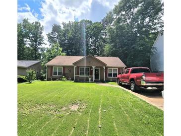 Charming single-story home featuring a lush green lawn, complementing the cozy architecture and inviting curb appeal at 107 Honeysuckle Ln, Stockbridge, GA 30281