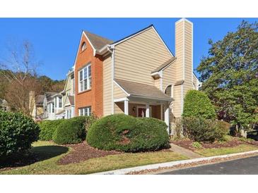A charming townhome featuring a mix of brick and beige siding, complemented by mature landscaping at 3050 Camden Way, Alpharetta, GA 30005