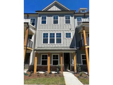 New construction townhome with a covered front porch, wood columns, and board and batten siding at 1616 Avery Way, Tucker, GA 30084