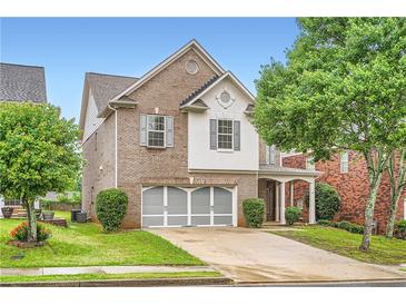 Charming two-story brick home features a two-car garage and well-manicured front yard at 909 Pine Cove Dr, Lilburn, GA 30047