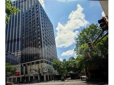 The building's exterior showcases modern architecture against a backdrop of trees and a blue sky with clouds at 20 Marietta Nw St # 10 F, Atlanta, GA 30303