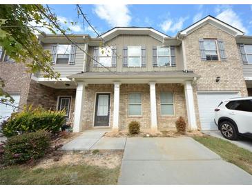 Charming townhome featuring a brick and gray facade, a covered porch, and a well-maintained lawn at 1560 Iris Walk, Jonesboro, GA 30238