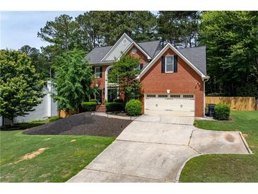Charming two-story brick home featuring a manicured lawn, mature trees, and a two-car garage at 220 Galesburg Dr, Lawrenceville, GA 30044