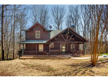 Charming log cabin featuring a welcoming front porch, exposed beams, and well-kept landscaping at 1225 Pitts Chapel, Newborn, GA 30056