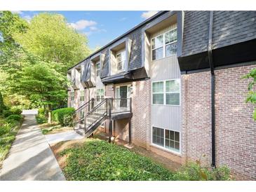 Brick and siding exterior of townhome with manicured lawn and black trim and stair railing at 305 Winding River Village Dr # F, Atlanta, GA 30350