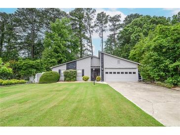 Charming gray home with manicured lawn and two-car garage nestled among mature trees at 5697 Brooklyn Ln, Norcross, GA 30093