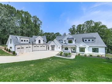Stunning white farmhouse-style home with a spacious lawn, and a five-car garage nestled among mature trees at 106 Belmont Dr, Canton, GA 30115