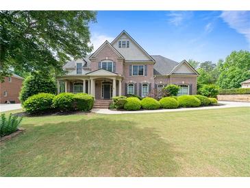Beautiful brick home with manicured lawn, lush shrubbery, and a covered front porch exudes curb appeal at 1758 Rosehedge Nw Way, Kennesaw, GA 30152