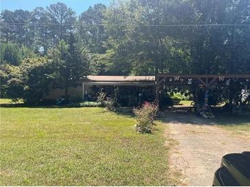 Ranch-style home on a spacious lot with mature trees and an ornamented wooden entrance structure at 1938 Brownsville Rd, Powder Springs, GA 30127