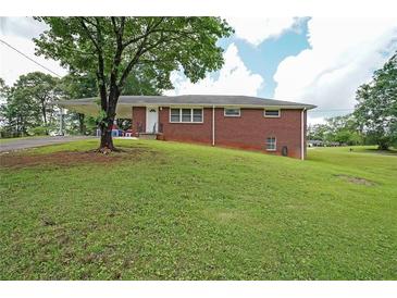 Charming brick home featuring a covered carport and a spacious front yard, perfect for outdoor activities at 629 Birchwood Rd, Marietta, GA 30060
