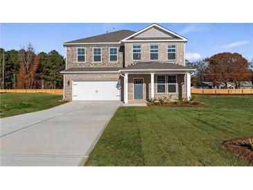 Charming two-story brick home featuring a covered porch and attached two-car garage at 124 Dalston Cv, Stockbridge, GA 30281