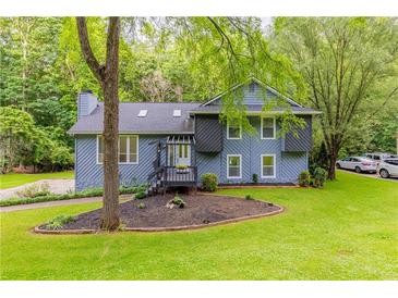Charming blue two-story home with a well-maintained lawn and front yard landscaping with mature trees at 288 Shire Way, Lawrenceville, GA 30044
