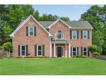 Beautiful brick home with a manicured lawn and symmetrical window design at 260 Roberts Rd, Suwanee, GA 30024