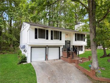 Split-level home featuring a 2-car garage, white siding, and lush greenery at 3512 Lynview W Ct, Decatur, GA 30034