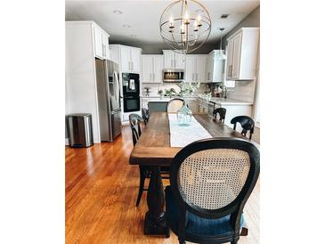Bright dining room features an expansive wood table, seating for six, and an elegant chandelier above at 4092 Grand Park Dr, Suwanee, GA 30024