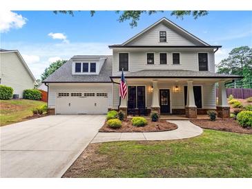 Charming two-story home with a well-manicured lawn, attached two-car garage, and a welcoming front porch with columns at 4092 Grand Park Dr, Suwanee, GA 30024