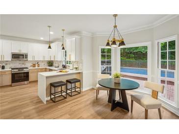 Bright kitchen featuring white cabinets, an island with seating, and a view of the outdoor pool at 2987 Windward Nw Dr, Kennesaw, GA 30152