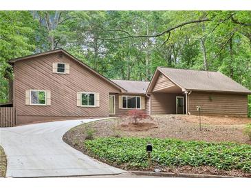 Charming home with wood siding, a curved driveway, and lush green landscaping provides great curb appeal at 402 Summit Ridge Ter, Lawrenceville, GA 30046