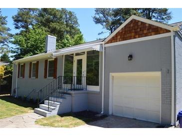 Charming brick home with a white garage door, screened porch, and mature landscaping at 2381 Eastway Rd, Decatur, GA 30033