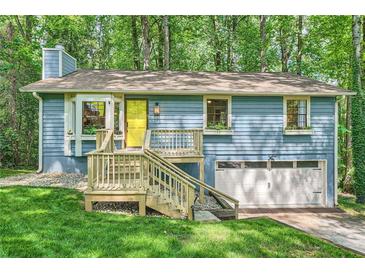 Charming blue home with a bright yellow door and a wooden porch surrounded by lush greenery at 2336 Vistamont Dr, Decatur, GA 30033