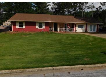 Charming single-story home with a vibrant red brick facade, complemented by a large, well-manicured front yard and mature trees at 1830 Brandy Se Ln, Conyers, GA 30013