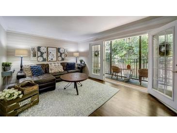 Cozy living room with a brown leather couch, decorative pillows, a wood table, and balcony access at 311 Peachtree Hills Ne Ave # 10C, Atlanta, GA 30305