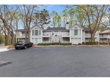 Condominium exterior with gray siding, a black roof, balconies, and ample parking at 204 Countryside Se Pl # 204, Smyrna, GA 30080