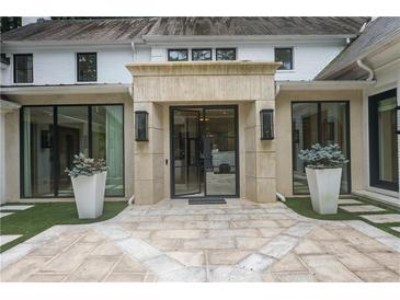 Striking front entrance features a stone patio, modern black framed glass door, and symmetrical planters and sconces at 1 Habersham Nw Way, Atlanta, GA 30305