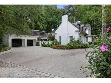 Elegant white brick home with a spacious driveway and a detached two-car garage at 1 Habersham Nw Way, Atlanta, GA 30305