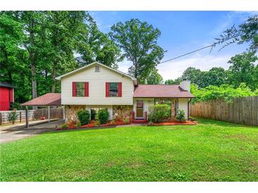 Charming home with a large front yard, carport, red shutters, and stone accents at 273 Hardwood Ln, Lawrenceville, GA 30044