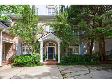 Charming brick home featuring a covered front entrance, mature trees, and a well-manicured landscaped yard at 4470 Crestwicke Pointe, Atlanta, GA 30319