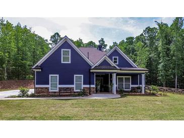 Charming blue house with a well-manicured lawn and inviting front porch surrounded by lush, mature trees at 1056 Riverstone Dr, Social Circle, GA 30025