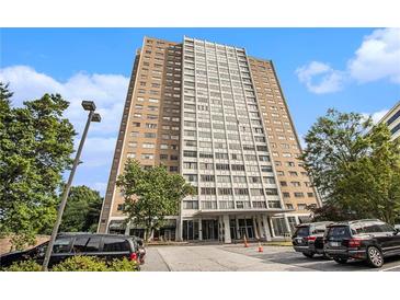 Modern high-rise building featuring a mix of brick and white concrete, mature trees, and ample parking at 215 Piedmont Ne Ave # 507, Atlanta, GA 30308