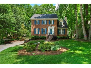 Charming two-story brick home with blue shutters and a well-manicured lawn and lush green trees at 1769 Milford Creek Sw Cts, Marietta, GA 30008