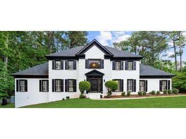 Elegant two-story white brick home with black trim, shutters, and lush landscaping at 1887 Chedworth Ct, Stone Mountain, GA 30087