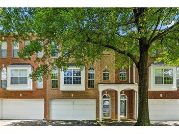Charming townhome featuring a brick facade, arched windows, a two-car garage, and a covered entryway at 576 Fraser Se St, Atlanta, GA 30312