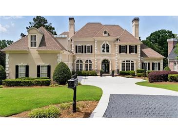 Elegant home with manicured lawn, circular driveway, and classic architectural details at 1409 Spyglass Hill Dr, Johns Creek, GA 30097