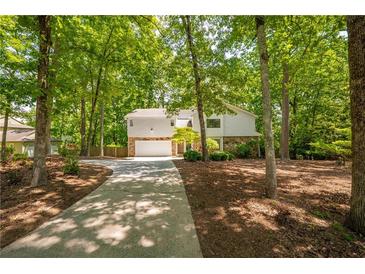 Charming home with stone accents, lush trees, and a long driveway at 110 Fairway Ridge Dr, Johns Creek, GA 30022