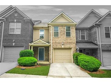 Inviting two-story brick townhome features a one-car garage, lush landscaping, and a welcoming front entrance at 1622 Honeysuckle Path, Conyers, GA 30012