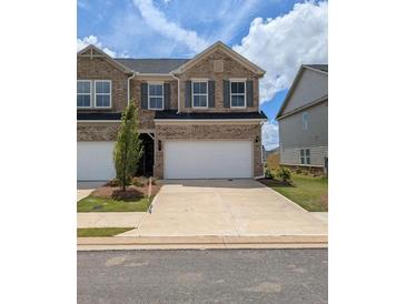 Brick townhouse featuring a two-car garage and a well-maintained front yard at 867 Pensive Run, Dacula, GA 30019