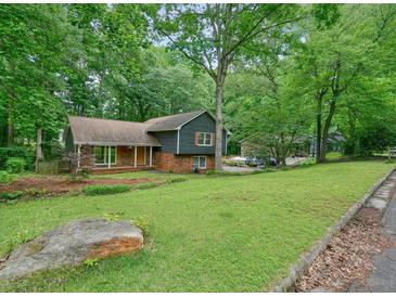 Charming home with a lush green yard, beautiful trees and stone and brick details at 588 Benson Hurst Sw Dr, Mableton, GA 30126