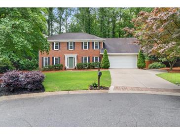 Charming two-story brick home featuring a manicured lawn, mature trees, and a two-car garage at 4507 Reva Way, Marietta, GA 30066