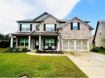 Charming two-story brick home with a well-manicured lawn and covered front porch perfect for relaxing at 2579 Wimberley Pine Ct, Dacula, GA 30019