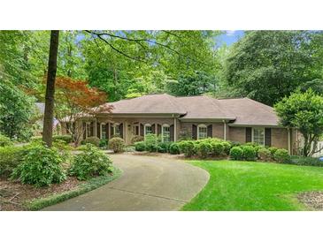 Charming one story brick home featuring a circular driveway and lush landscaping with mature trees at 11190 Hembree Springs Dr, Roswell, GA 30076