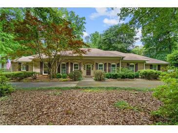 Charming brick home with a well-manicured lawn, mature trees, and welcoming front entrance at 11190 Hembree Springs Dr, Roswell, GA 30076
