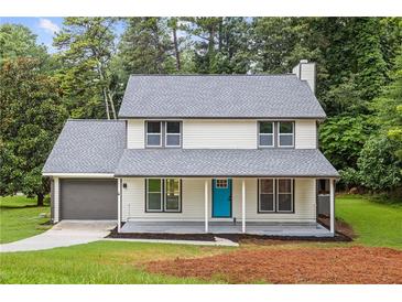 Charming two-story home with a welcoming front porch and a new gray roof, set amongst mature trees at 4657 Lou Ivy Rd, Peachtree Corners, GA 30096